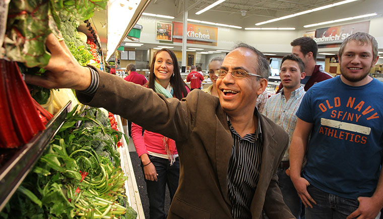 Agriculture teacher in a grocery store with students, reaching for producef