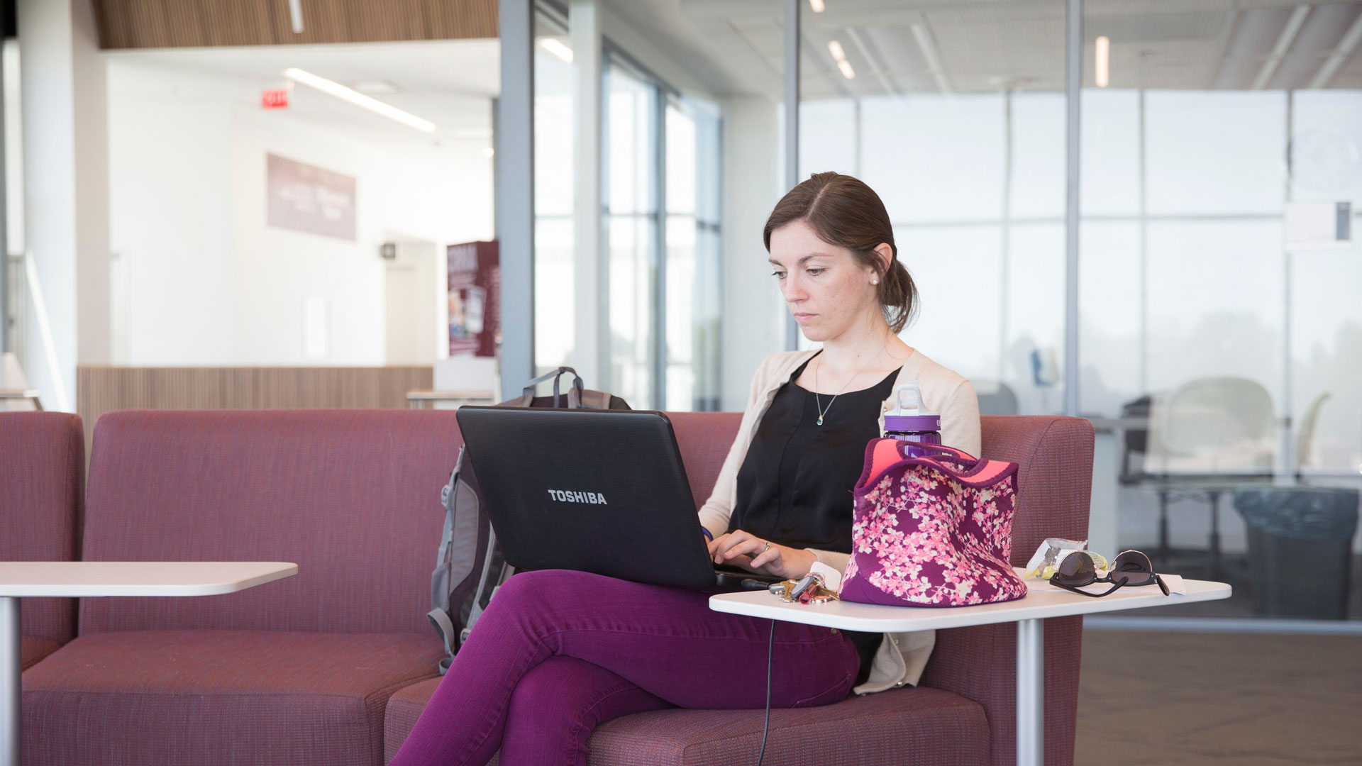 Student sitting on couch using her laptop to study
