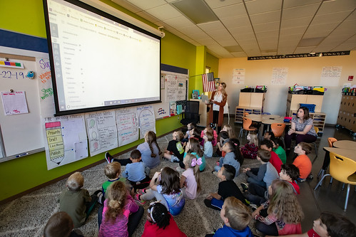 Kids in a classroom looking at the screen with their teacher