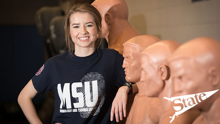 Female student posing with a practice dummy