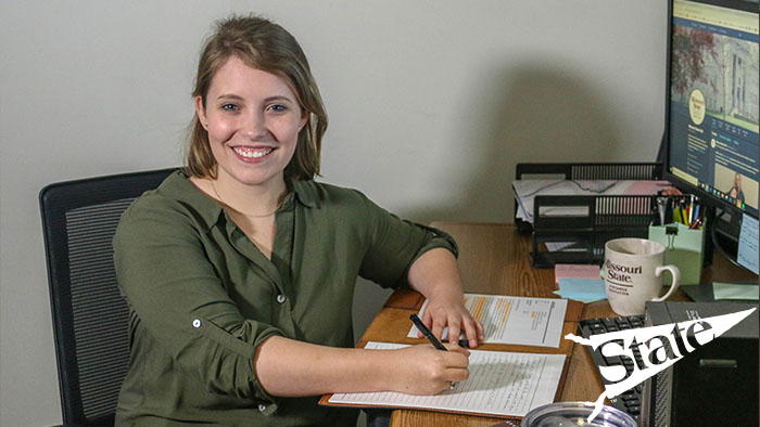 Smiling Missouri State graduate student sitting at her computer writing.