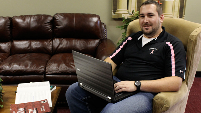 Online graduate student sitting in chair with laptop.