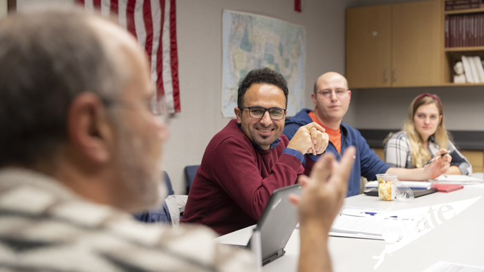 a group of individuals sitting around a table, discussing public management